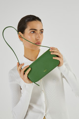 Profile view of model wearing the Oroton Muse Apple Mini Baguette in Orchard and AppleSkin™: 20% GRS (Global Recycled Standard) Polyester, 16% GRS Cotton, 26% Apple Waste, 38% Polyurethane for Women