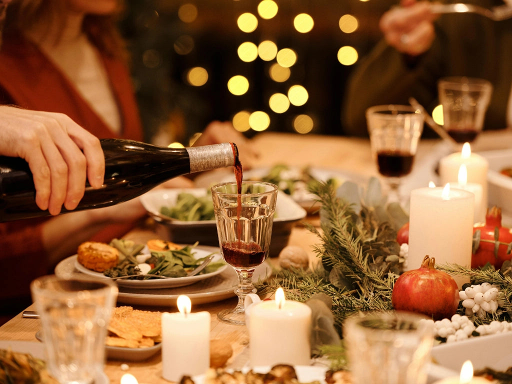 Person pouring a glass of wine at the table for Christmas dinner