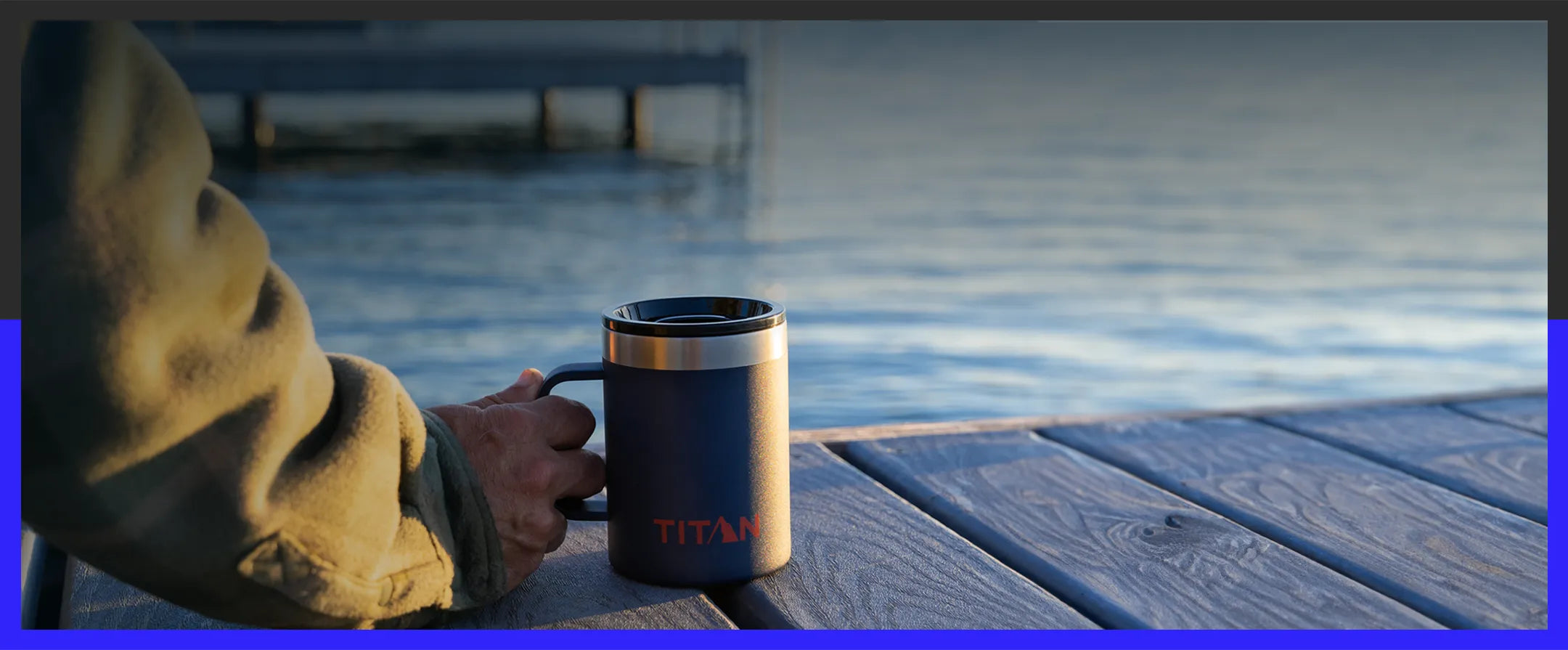 Person holding a Titan by Arctic Zone 14 Oz Stainless Steel Mug while sitting on a dock, watching the sunset